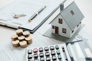 Husmodell med fastighetsmäklare och kund diskuterar för kontrakt att köpa hus, försäkring eller lån fastigheter bakgrund.